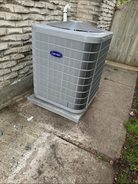 Carrier air conditioner condenser installed on a concrete pad at the side of a London home