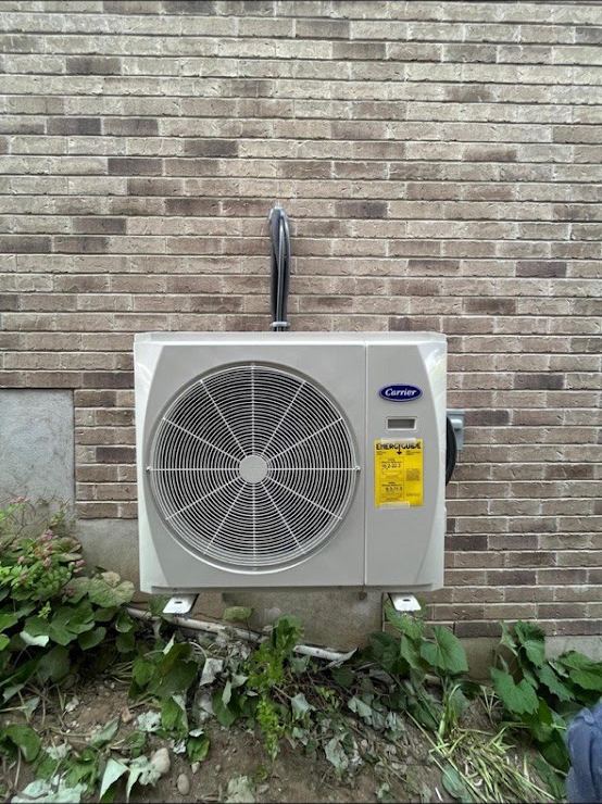 Carrier heat pump outdoor unit wall mounted on the brick of a London home